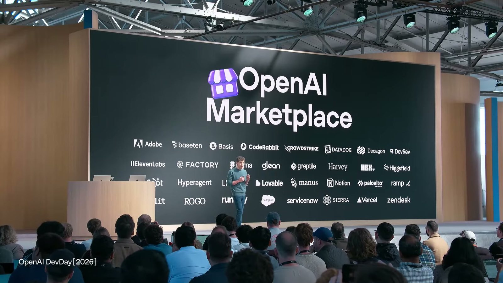 舞台大螢幕中央是 OpenAI Marketplace 字樣與商店圖示，四周排滿數十家合作夥伴的標誌